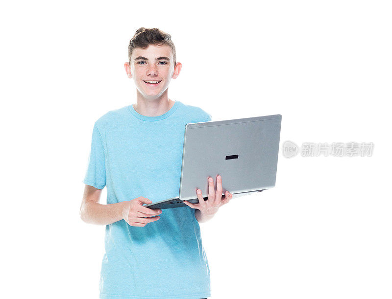 看着镜头/只有一个人/一个人/完整的长度/一个12-13岁的男孩英俊的人白人男性/年轻男子/男孩/十几岁的男孩在白人背景下工作和使用笔记本电脑/电脑